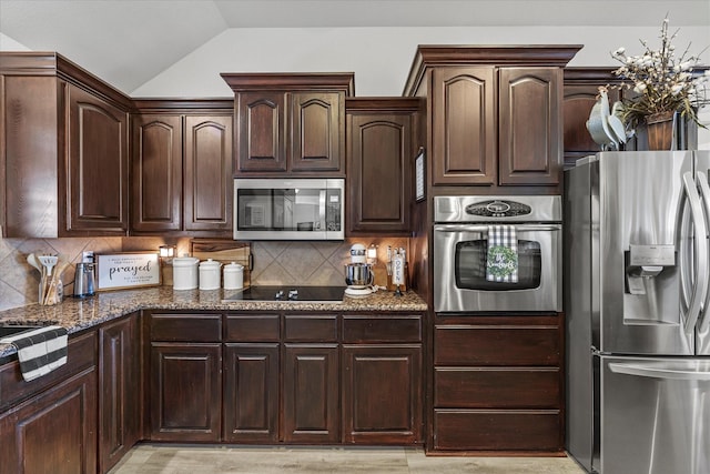 kitchen with backsplash, dark brown cabinetry, stainless steel appliances, and dark stone countertops