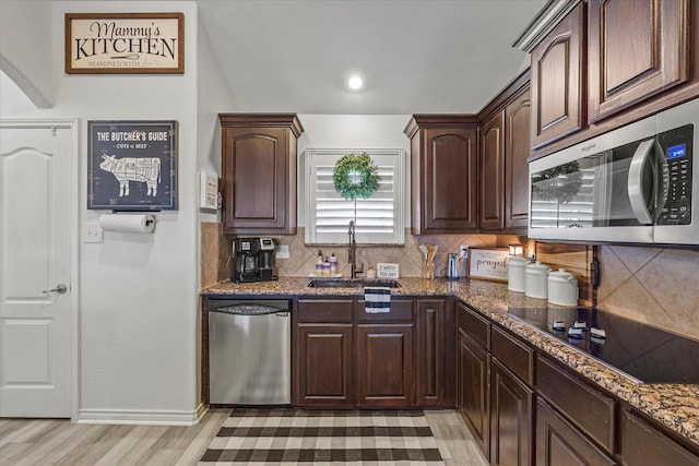 kitchen with sink, dark stone countertops, backsplash, stainless steel appliances, and dark brown cabinets