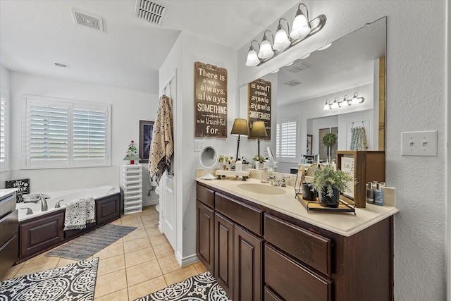 bathroom with a washtub, vanity, and tile patterned flooring