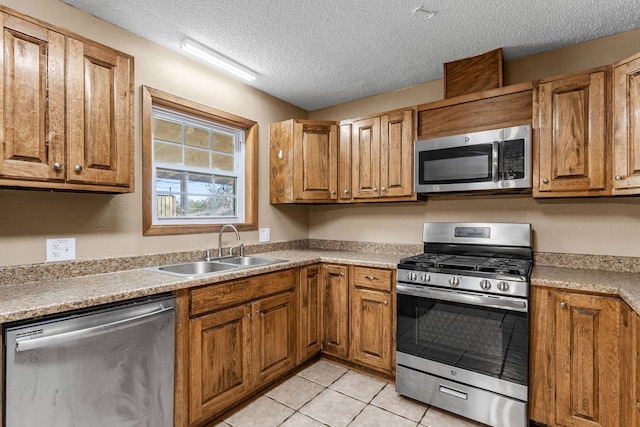 kitchen featuring a textured ceiling, sink, light tile patterned floors, and stainless steel appliances