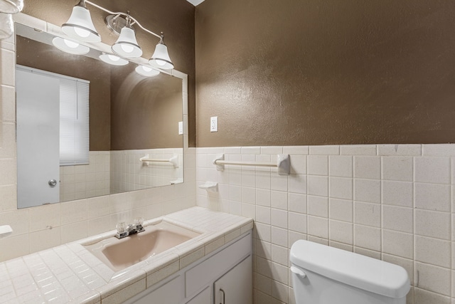 bathroom featuring toilet, vanity, and tile walls