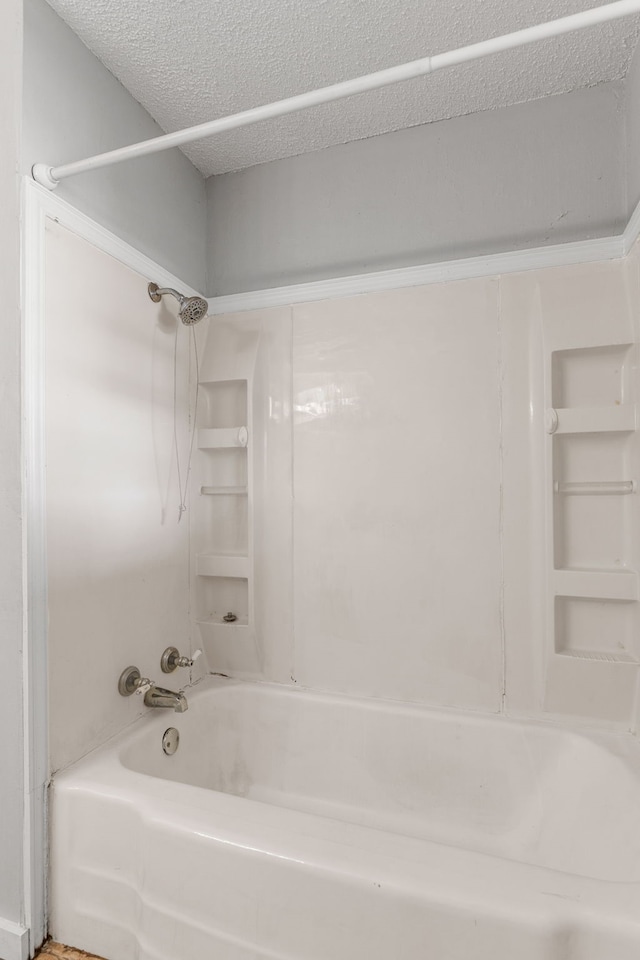 bathroom featuring bathtub / shower combination and a textured ceiling