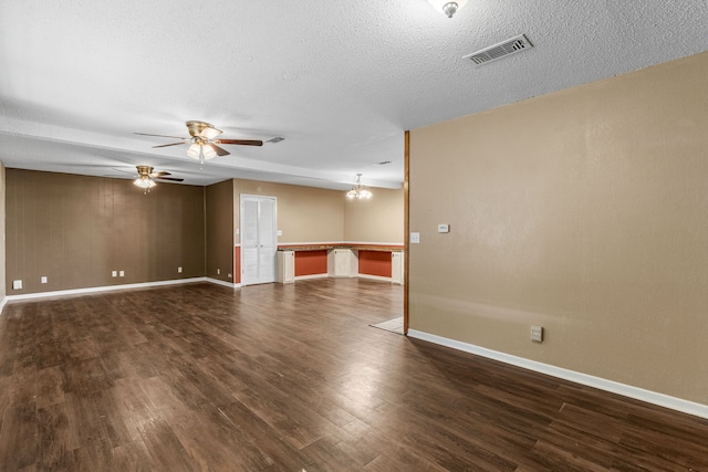 spare room with dark wood-type flooring, a textured ceiling, and ceiling fan with notable chandelier