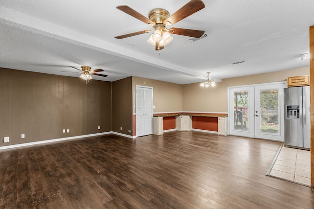 unfurnished living room with a textured ceiling, french doors, hardwood / wood-style flooring, and ceiling fan with notable chandelier