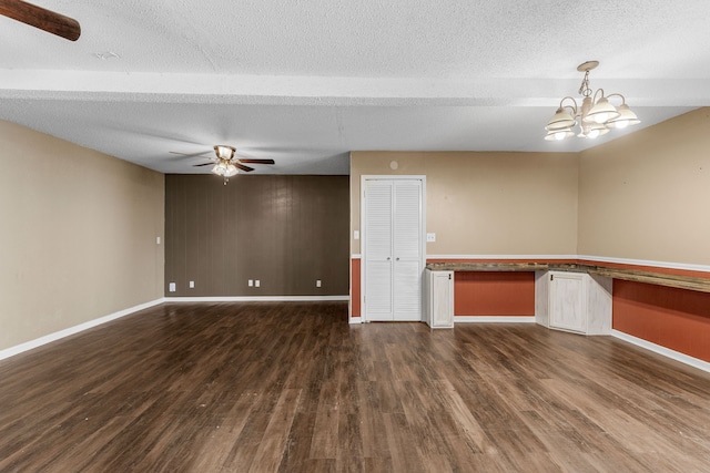 empty room featuring a textured ceiling, ceiling fan with notable chandelier, and dark hardwood / wood-style floors