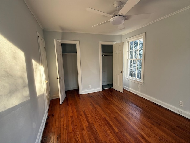 unfurnished bedroom featuring dark hardwood / wood-style flooring, two closets, ceiling fan, and ornamental molding