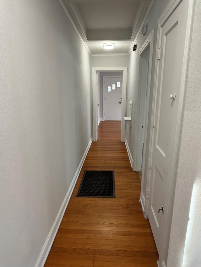 corridor with ornamental molding and hardwood / wood-style flooring