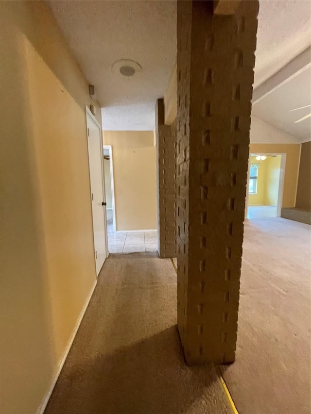 hallway featuring lofted ceiling, a textured ceiling, and light carpet