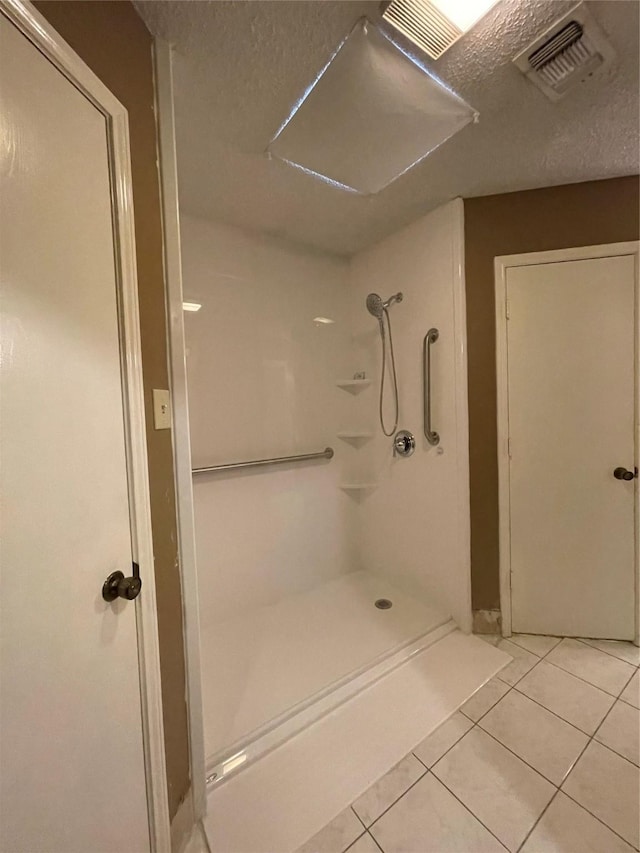 bathroom with a textured ceiling, walk in shower, and tile patterned flooring