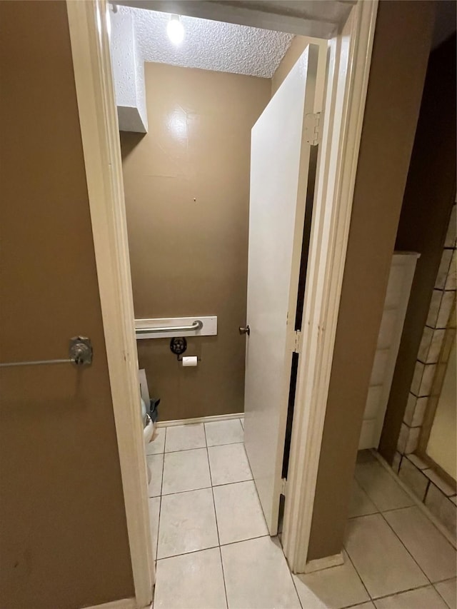 bathroom with a textured ceiling, tile patterned floors, and toilet