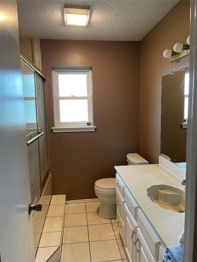 full bathroom featuring a textured ceiling, tile patterned flooring, combined bath / shower with glass door, toilet, and vanity