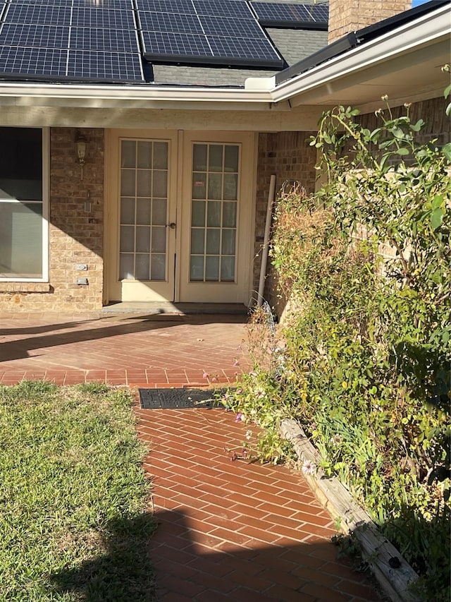 view of exterior entry with french doors and solar panels