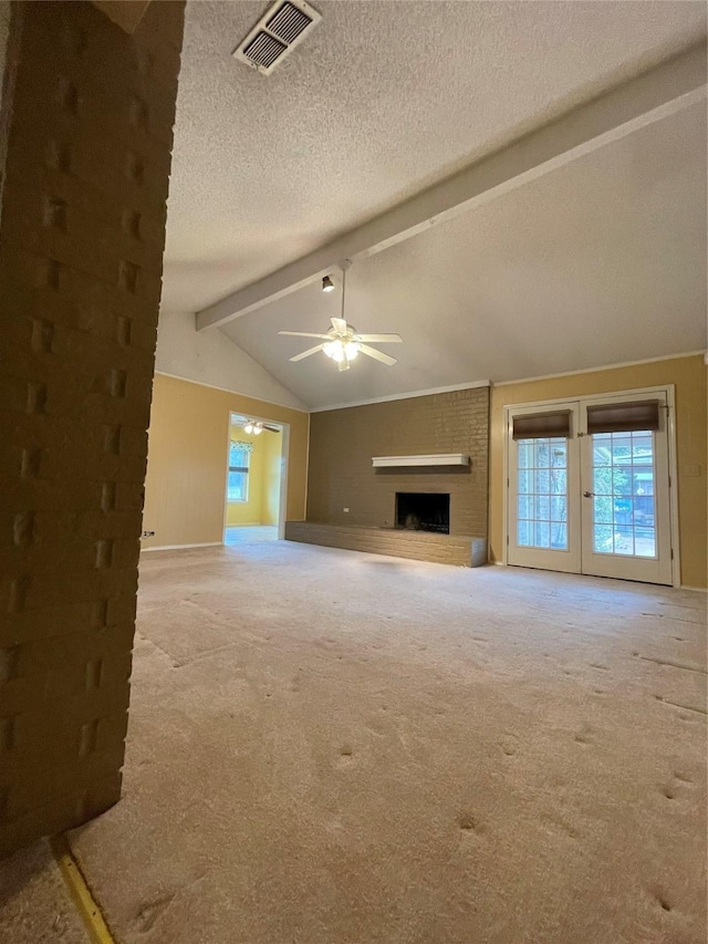 unfurnished living room with a textured ceiling, light colored carpet, a fireplace, ceiling fan, and vaulted ceiling with beams