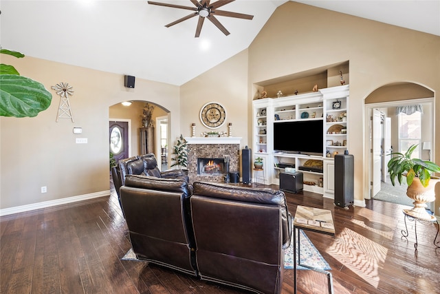 living room featuring ceiling fan, a fireplace, high vaulted ceiling, and dark wood-type flooring