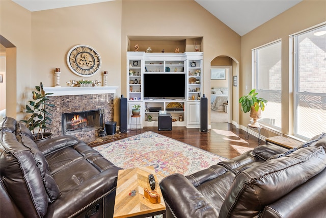 living room with dark hardwood / wood-style flooring, lofted ceiling, and a tiled fireplace