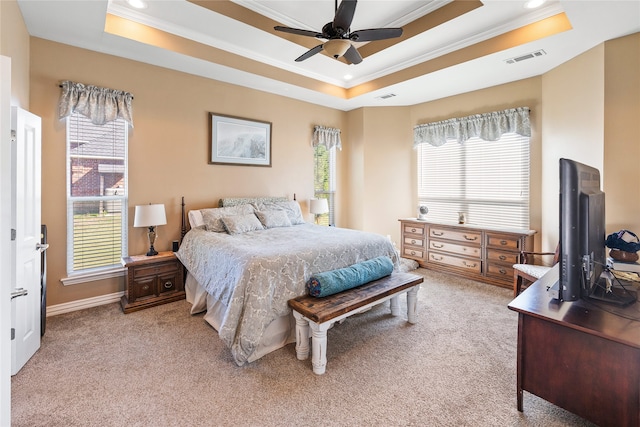 carpeted bedroom featuring a tray ceiling, multiple windows, and ceiling fan