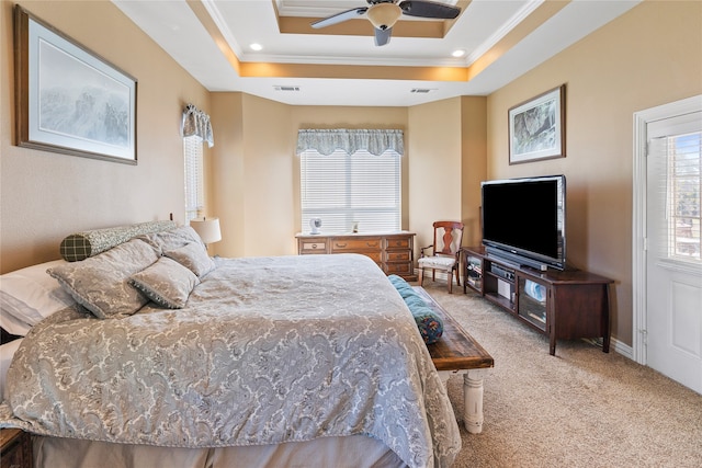 bedroom with a raised ceiling, ceiling fan, light colored carpet, and ornamental molding