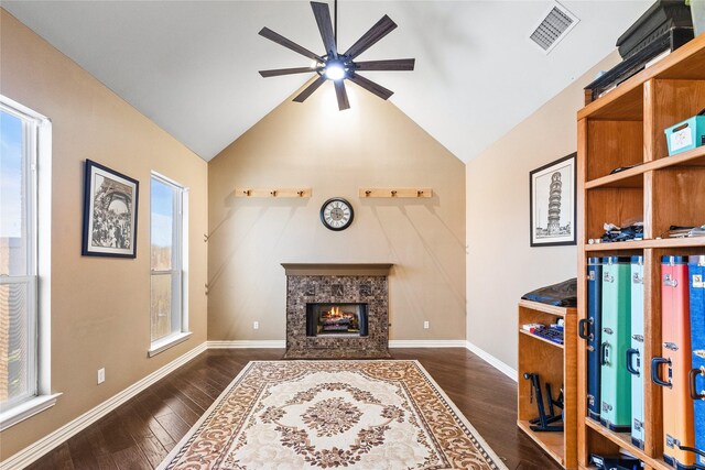 living room featuring ceiling fan, dark wood-type flooring, a tile fireplace, and vaulted ceiling