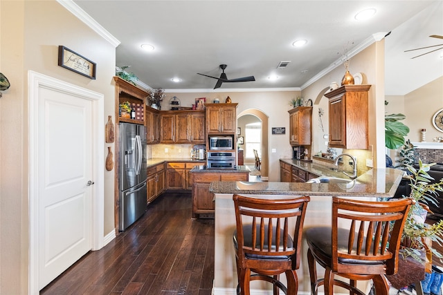 kitchen with kitchen peninsula, ornamental molding, stainless steel appliances, sink, and dark hardwood / wood-style floors