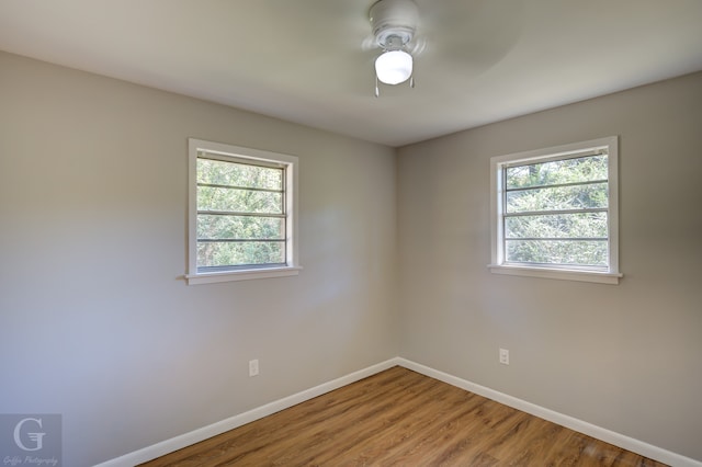 unfurnished room featuring a wealth of natural light, hardwood / wood-style floors, and ceiling fan