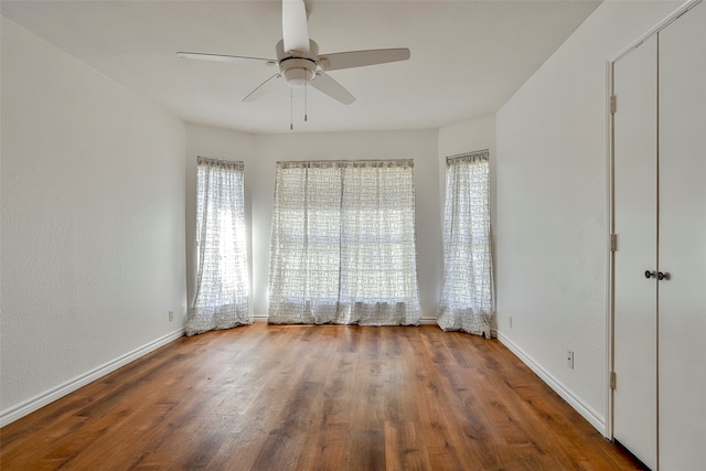 spare room featuring hardwood / wood-style floors, ceiling fan, and a healthy amount of sunlight