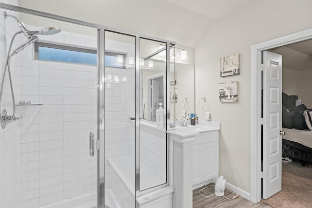 bathroom featuring hardwood / wood-style flooring, vanity, a shower with door, and vaulted ceiling