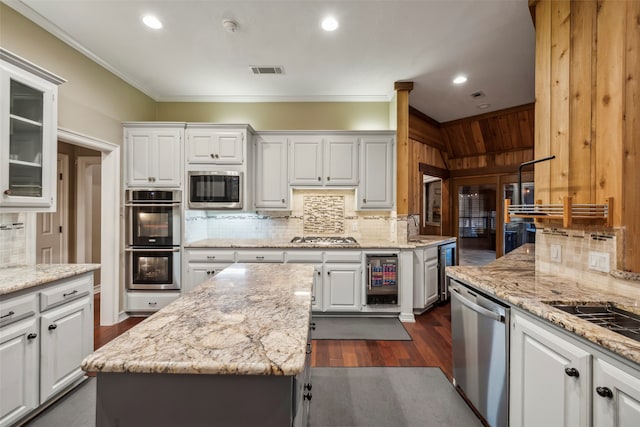 kitchen with beverage cooler, a center island, white cabinets, crown molding, and appliances with stainless steel finishes