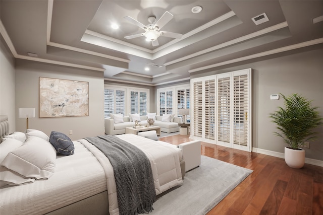 bedroom featuring ornamental molding, dark hardwood / wood-style floors, ceiling fan, and a tray ceiling