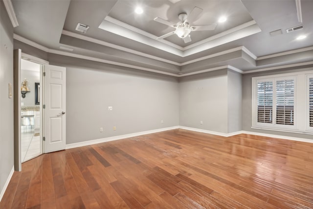 spare room with hardwood / wood-style floors, ceiling fan, crown molding, and a tray ceiling