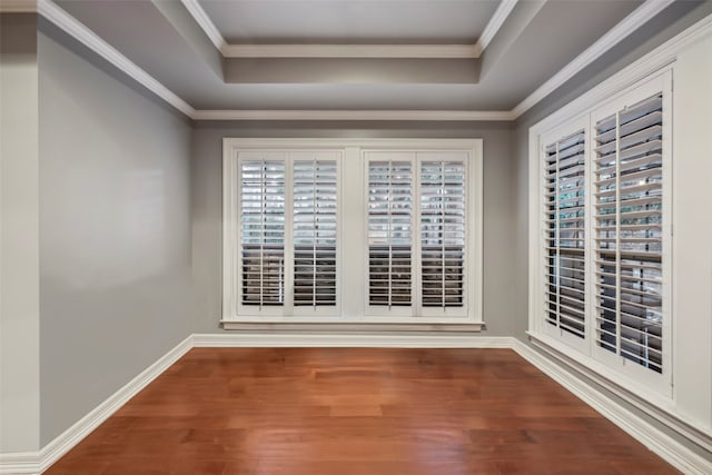 empty room featuring a wealth of natural light, ornamental molding, a tray ceiling, and hardwood / wood-style flooring