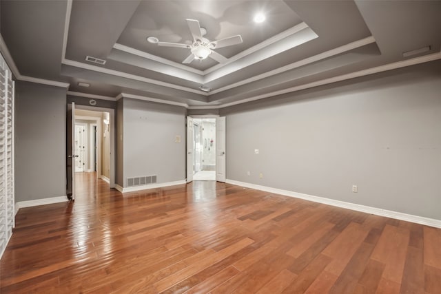 spare room featuring ornamental molding, hardwood / wood-style flooring, a raised ceiling, and ceiling fan