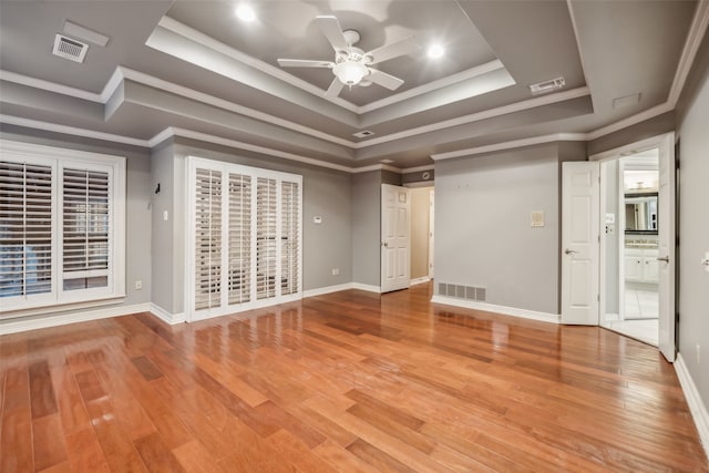 spare room featuring ornamental molding, hardwood / wood-style floors, ceiling fan, and a raised ceiling