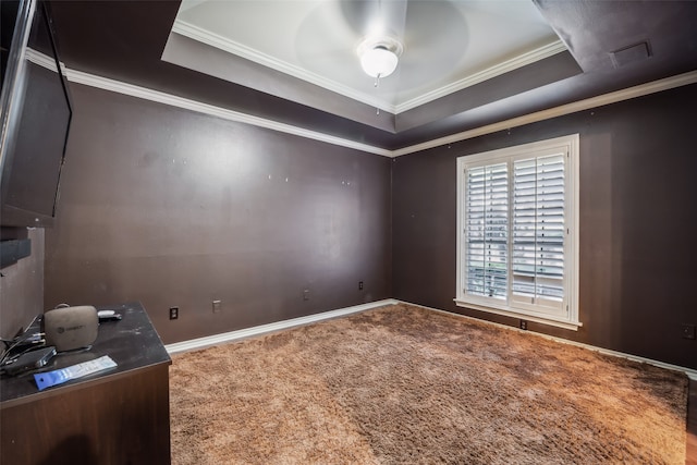 empty room featuring carpet floors, ornamental molding, ceiling fan, and a raised ceiling