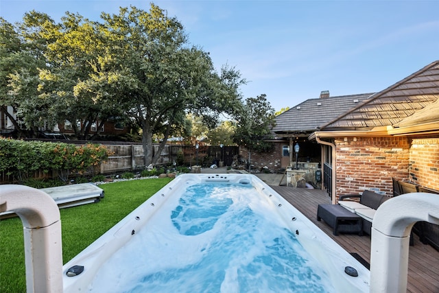 view of swimming pool with a lawn, an outdoor hot tub, and a wooden deck