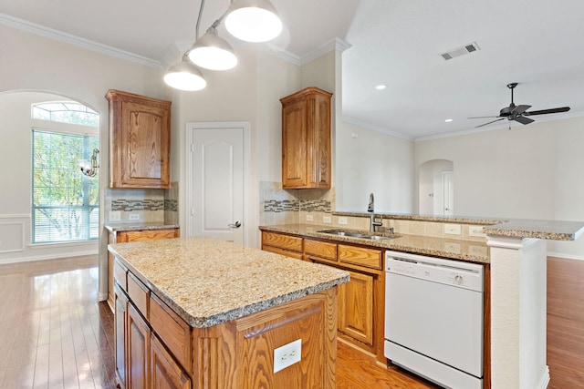 kitchen featuring white dishwasher, plenty of natural light, sink, and a center island