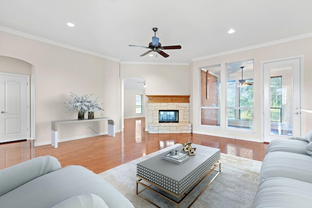 living room featuring light hardwood / wood-style floors, ceiling fan, a healthy amount of sunlight, and crown molding