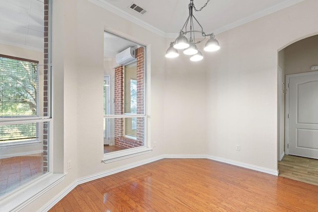 unfurnished dining area featuring an inviting chandelier, light wood-type flooring, crown molding, and a wall mounted air conditioner