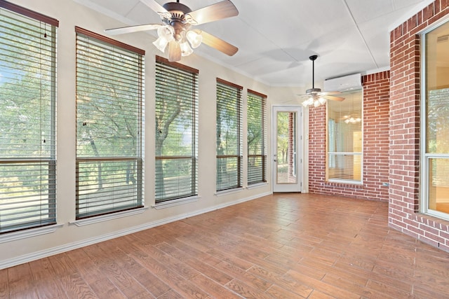 unfurnished sunroom featuring a wall unit AC, ceiling fan, and plenty of natural light