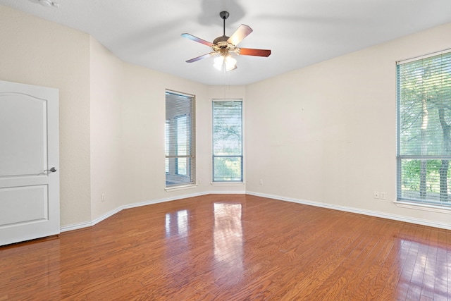 empty room featuring ceiling fan, wood-type flooring, and plenty of natural light