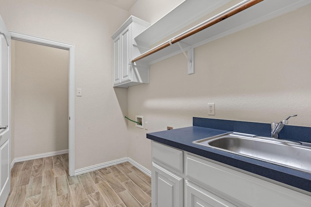 clothes washing area featuring hookup for a washing machine, cabinets, sink, and light hardwood / wood-style floors