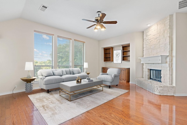 living room with a fireplace, hardwood / wood-style flooring, ceiling fan, and vaulted ceiling