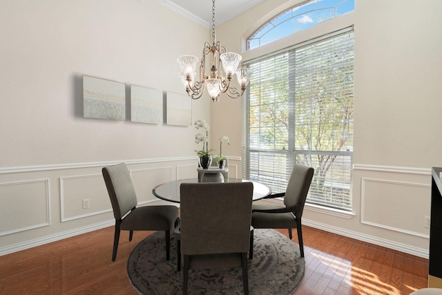 dining room featuring hardwood / wood-style floors, a healthy amount of sunlight, crown molding, and an inviting chandelier