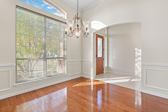 unfurnished dining area featuring light hardwood / wood-style floors, a notable chandelier, and ornamental molding