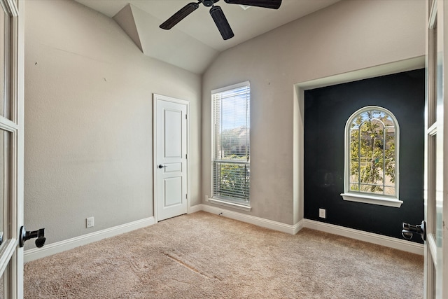 carpeted spare room with plenty of natural light, lofted ceiling, and ceiling fan