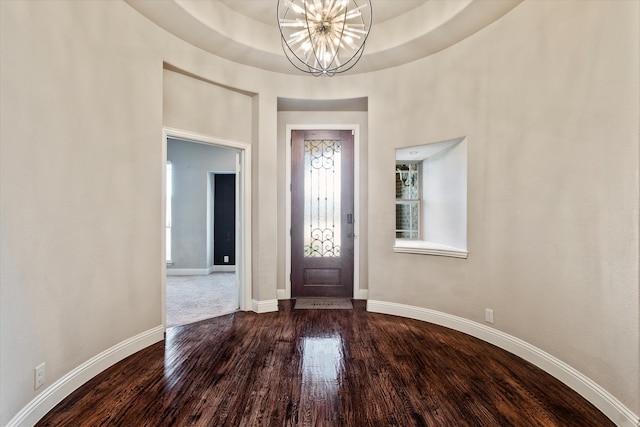 entryway with wood-type flooring, a tray ceiling, and a notable chandelier