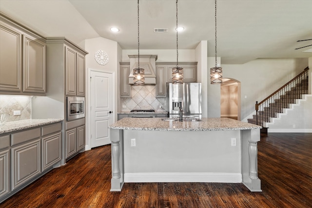 kitchen featuring a center island with sink, appliances with stainless steel finishes, and dark wood-type flooring