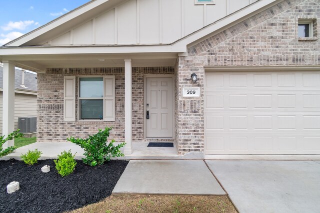 doorway to property featuring a garage, central AC, and a porch