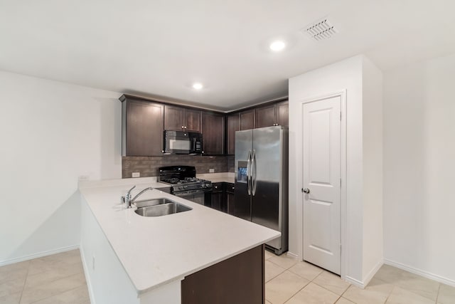 kitchen with kitchen peninsula, dark brown cabinetry, black appliances, sink, and backsplash