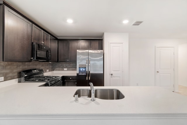 kitchen featuring kitchen peninsula, dark brown cabinetry, black appliances, sink, and tasteful backsplash