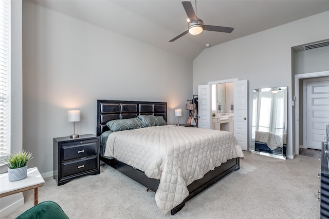 bedroom featuring ceiling fan, connected bathroom, light carpet, and vaulted ceiling